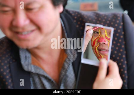 (190402) -- JINPING, 2. April 2019 (Xinhua) -- Ein Schüler schaut in den Spiegel, während er sein Gesicht zur Vorbereitung auf den Drachentanz in der Longli Mittel- und Grundschule im Jinping County, Provinz Guizhou im Südwesten Chinas, am 20. März 2019 malte. Longlis Drachentanz wurde 2005 als immaterielles Kulturerbe der Provinz Guizhou klassifiziert und hat eine Geschichte von mehr als 600 Jahren. Es zeichnet sich durch das schöne Gesicht der Tänzer aus. Seit 2008 wird Longlis Drachentanz in die Longli-Mittel- und Grundschule eingeführt, deren Schüler zwei Stunden pro Woche mit Drachentanz Mas genießen Stockfoto