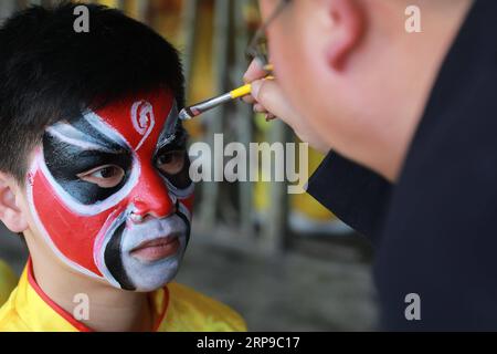 (190402) -- JINPING, 2. April 2019 (Xinhua) -- Ein Lehrer malt das Gesicht seines Schülers in Vorbereitung auf den Drachentanz in der Longli Mittel- und Grundschule im Jinping County, Provinz Guizhou im Südwesten Chinas, am 20. März 2019. Longlis Drachentanz wurde 2005 als immaterielles Kulturerbe der Provinz Guizhou klassifiziert und hat eine Geschichte von mehr als 600 Jahren. Es zeichnet sich durch das schöne Gesicht der Tänzer aus. Seit 2008 wird Longlis Drachentanz in die Longli Middle and Primary School eingeführt, deren Schüler zwei Stunden pro Woche mit Drachentanzmeistern verbringen, um Kosten zu lernen Stockfoto