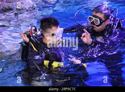 (190402) -- QINGDAO, 2. April 2019 (Xinhua) -- Ein Coach tröstet und ermutigt Zheng Senyou (L) beim Tauchen in Qingdao, Ostchinas Provinz Shandong, am 1. April 2019. Zheng Senyou, ein 16-jähriger Teenager, wurde im Alter von vier Jahren mit Autismus diagnostiziert. Als autistisches Kind leidet er unter sozialen und sprachlichen Beeinträchtigungen. Da die allgemeine medizinische Behandlung wenig half, suchten Zheng und seine Familie nach Möglichkeiten und lernten DFH (Diving for Humanity) kennen, eine nicht profitable Organisation und die Tauchbehandlung. Nach einer neunmonatigen Behandlung wurde seine Beeinträchtigung gelindert. Einen Tag vor dem Stockfoto