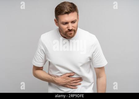 Unwohlsein Mann mittleren Alters, der an Verdauungsstörungen leidet und kranke Magenschmerzen berührt isoliertes Studio Stockfoto