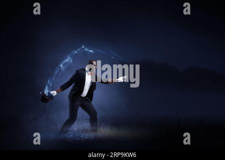 Männlicher Illusionist, der Tricks ausführt. Gemischte Medien Stockfoto