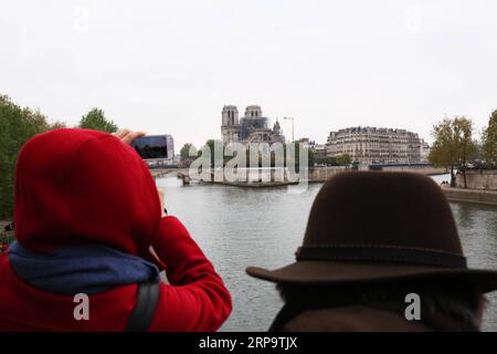 (190417) -- PARIS, 17. April 2019 (Xinhua) -- Menschen beobachten die Kathedrale Notre Dame nach einem Brand in Paris, Frankreich, am 16. April 2019. Der französische Präsident Emmanuel Macron versprach am Dienstag, innerhalb von fünf Jahren die Kathedrale Notre Dame, die am Montagabend vom Feuer verwüstet wurde, wieder aufzubauen und forderte die Franzosen auf, vereint zu bleiben. Am frühen Montagabend brach in der berühmten Kathedrale ein Feuer aus. Online-Aufnahmen zeigten dicken Rauch, der von der Spitze der Kathedrale wehte, und riesige Flammen zwischen ihren beiden Glockentürmen, die den Turm und das gesamte Dach umschlossen, die beide später zusammenbrachen. (Xinhua/Gao Jing) FRANKREICH-PARIS-NOT Stockfoto