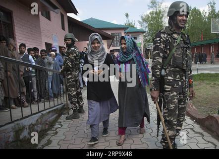 (190418) -- SRINAGAR, 18. April 2019 (Xinhua) -- indische paramilitärische Truppen stehen Wache, wenn Kaschmirfrauen aus einer Wahlstation kommen, nachdem sie ihre Stimmen während der zweiten Phase der indischen Parlamentswahlen abgegeben haben, am Stadtrand von Srinagar, der Sommerhauptstadt des von Indien kontrollierten Kaschmirs, am 18. April 2019. (Xinhua/Javed dar) KASCHMIR-SRINAGAR-WAHL-ZWEITE PHASE PUBLICATIONxNOTxINxCHN Stockfoto