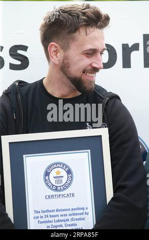 (190428) -- ZAGREB, 28. April 2019 -- Tomislav Lubenjak hält das Guinness-Zertifikat, nachdem er den Guinness-Weltrekord gebrochen hat, weil er ein Auto am weitesten in 24 Stunden von einer Person in Zagreb, Kroatien, am 28. April 2019, geschoben hat. Lubenjak startete am Samstag um 15 Uhr und hielt am Sonntag um etwa 14:20 Uhr an, nachdem er das Smart Car mit einem Fahrer 106,938 Kilometer lang im Inneren geschoben hatte. ) KROATIEN-ZAGREB-GUINNESS WELTREKORDWAGEN, DER MATIJAXHABLJAK PUBLICATIONXNOTXINXCHN SCHIEBT Stockfoto