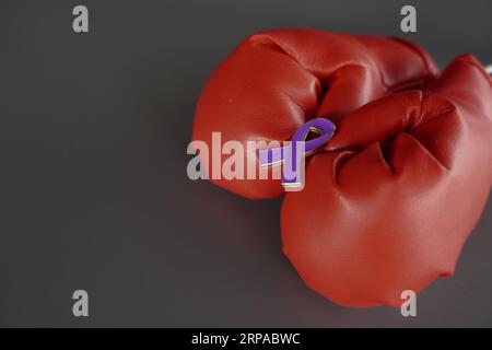 Nahaufnahme von Boxhandschuhen und lilafarbenem Band mit Kopierraum. Pankreaskarzinom, Epilepsie und Alzheimer-Erkrankungskonzept Stockfoto