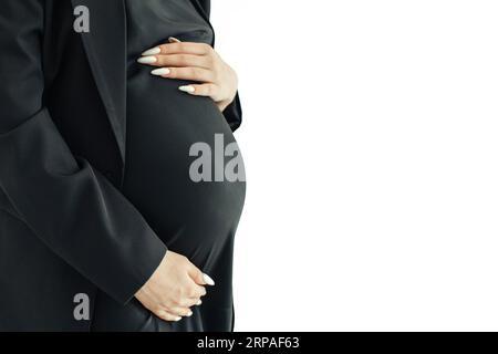 Das Konzept der Schwangeren. Eine schwangere Frau in schwarzer Kleidung hält ihren Bauch mit den Händen, daneben auf weißem Hintergrund ist Freiraum für Stockfoto