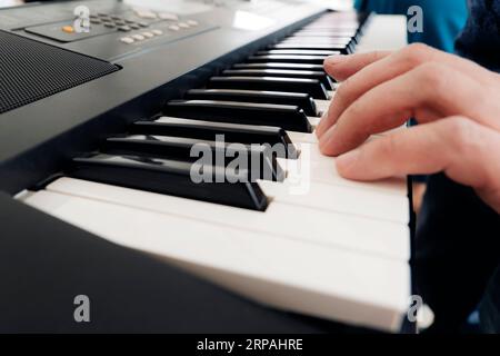 Das Konzept des Musikinstrumentenspiels - die Hände der Männer am Klavier spielen eine berühmte Melodie. Konzentrieren Sie sich auf die Finger und die Klaviertasten Stockfoto