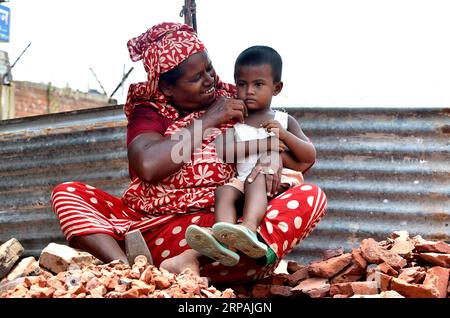 (190513) -- PEKING, 13. Mai 2019 -- Ein Kind sitzt am 12. Mai 2019 in Narayanganj am Stadtrand von Dhaka, Bangladesch, auf dem Bein ihrer berufstätigen Mutter. Stringer) XINHUA-FOTOS DES TAGES Naim-ul-karim PUBLICATIONxNOTxINxCHN Stockfoto