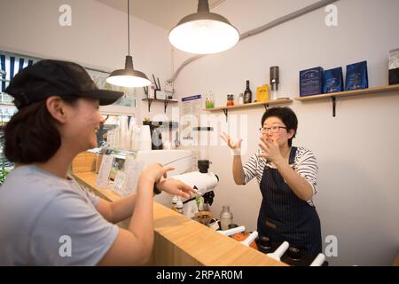 (190517) -- HANGZHOU, 17. Mai 2019 (Xinhua) -- Yang Di (R) kommuniziert mit einem Kunden in ihrem Coffee Shop in Hangzhou, Ostchinesische Provinz Zhejiang, 17. Mai 2019. Lu Jun und Yang Di sind ein schwerhöriges Paar, das in Hangzhou lebt. Mit Hilfe des örtlichen Arbeitsvermittlungszentrums für behinderte Menschen lernten sie, Kaffee zu machen, und schafften es später, im März 2019 im Westen der Stadt ein Café namens Sign Coffee zu gründen. In der täglichen Zeit kommuniziert das Paar mit den Kunden durch Gebärdensprache oder schriftliche Wörter. (Xinhua/Weng Xinyang) CHINA-HANGZHOU-COFFEE SHOP (CN) PUBLICATIONxNOTxINxCHN Stockfoto