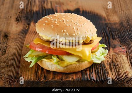 Rindfleisch-Cheeseburger mit Gemüse und Käsesauce auf Holzbrett Stockfoto