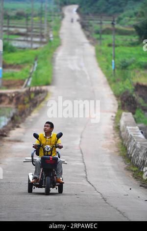 (190519) -- NANCHANG, 19. Mai 2019 (Xinhua) -- Lin Fusheng reitet mit einem Dreirad zu einem Kreativindustriepark für Ölmalerei im Bezirk Lichuan, ostchinesische Provinz Jiangxi, 16. Mai 2019. LIN Fusheng, ein Dorfbewohner aus dem Dorf Hualian in der Gemeinde Huashan im Landkreis Lichuan, litt an körperlicher Behinderung aufgrund einer Kinderlähmung. Trotzdem blieb Lin bei seinem Traum, Maler zu werden. Als Lichuan County 2013 eine rapide Entwicklung der Ölmalerei erlebte, kehrte Lin in seine Heimatstadt zurück und wuchs mit Hilfe der lokalen Regierung als professioneller Maler an. Jetzt besitzt Lin ein Studio bei Stockfoto