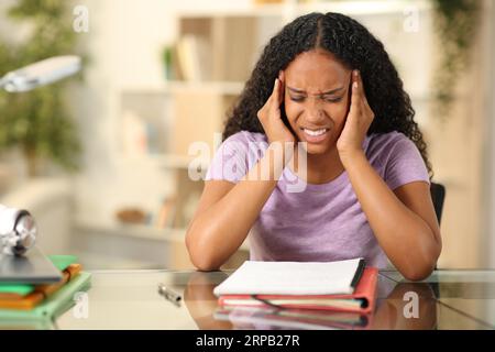Schwarze Studenten leiden unter Kopfschmerz, indem sie zu Hause Notizen auswendig lernen Stockfoto