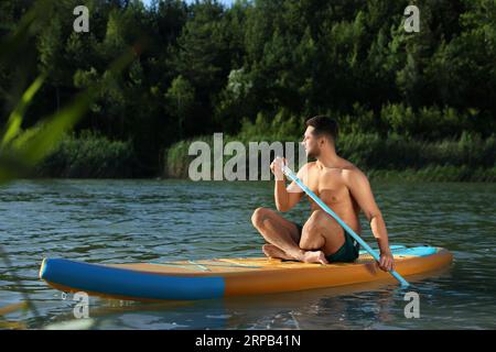 Mann paddeln auf dem SUP-Brett im Fluss Stockfoto