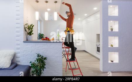 Elektriker repariert Deckenventilator mit Lampen im Innenbereich. Platz für Text. Stockfoto