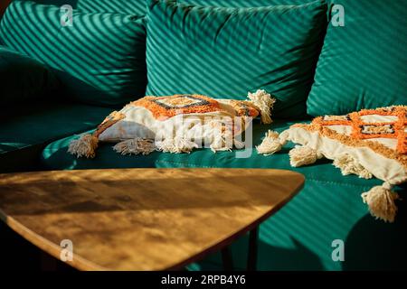 Wohnzimmer mit grünem Sofa und Couchtisch mit Sonnenlicht. Entspannen Sie sich in einem gemütlichen Zuhause. Stockfoto