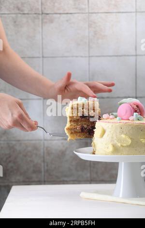 Frau, die ein Stück leckeren Kuchen am weißen Holztisch nimmt, Nahaufnahme Stockfoto