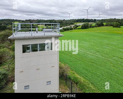 01. September 2023, Sachsen, Heinersgrün: Der neu renovierte Grenzturm Heinersgrün im Vogtland, einst Teil des Todesstreifens an der innerdeutschen Grenze (Luftaufnahme mit Drohne). Der steinerne Zeuge des DDR-Grenzregimes wird künftig als Zweigstelle des Deutsch-Deutschen Museums Mödlareuth dienen und für Besucher zu Führungen geöffnet sein. Der Turm war 1978 als so genannter Kommandoposten in Betrieb genommen worden. Es ist eines der letzten Relikte der DDR-Grenzsicherung zwischen Sachsen und Bayern. Foto: Jan Woitas/dpa Stockfoto