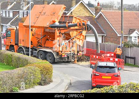 Der Fahrer wartet und beobachtet, wie er die Spitze hebt und den vollen Abfallbehälter aus der Absaugmaschine des LKW-LKWs in die temporäre Müllhalde Großbritannien entlädt Stockfoto