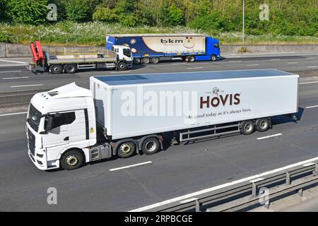 Seitenansicht von vorn, lkw-Lastwagen mit Lastwagen und Hovis Ltd. Mit Knickgelenkauflieger für Mehl- und Brothersteller, die entlang der Autobahn M25 in Großbritannien fahren Stockfoto