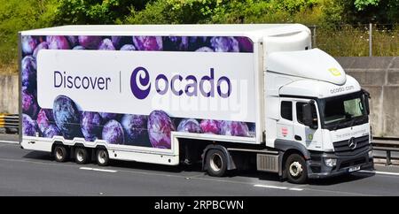 Weißer lkw-Lastkraftwagen, Antriebseinheit mit aerodynamischem Abweiser über dem Fahrerhaus, Ocado-Banner über knickgelenktem Auflieger auf der Autobahn M25 UK Stockfoto