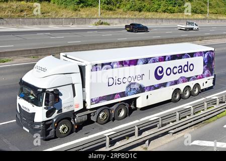 Luftaufnahme weißer LKW-Lkw-Antrieb aerodynamischer Abweiser über der Kabine Entdecken Sie das Ocado-Banner auf knickgelenktem Auflieger auf der M25-Autobahn in Großbritannien Stockfoto