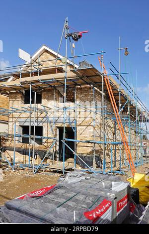 Elektrische Hebevorrichtung in Position auf Gerüst zum Anheben von Marley Betonziegeln Ziegelgiebelende fertiggestellt auf neu gebauter freistehender Wohnanlage England UK Stockfoto