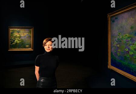 (190607) -- PEKING, 7. Juni 2019 (Xinhua) -- Marianne Mathieu, wissenschaftliche Direktorin des Musee Marmottan Monet, posiert für ein Foto mit Werken Claude Monets in der National Gallery of Australia (NGA) in Canberra, Australien, 6. Juni 2019. (Xinhua/Pan Xiangyue) XINHUA FOTOS DES TAGES PUBLICATIONxNOTxINxCHN Stockfoto