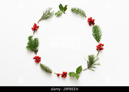 Rundes Weihnachtsgestell aus holly Beeren und grünen Zweigen. Flach, Draufsicht, Kopierbereich. Stockfoto