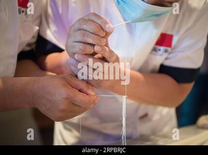 (190615) -- PEKING, 15. Juni 2019 (Xinhua) -- Köche fädeln handgezogene Nudeln durch eine Nadel während einer Promotion auf Chinas Qinghai-Ramen in Kairo, Ägypten, am 14. Juni 2019. (Xinhua/Wu Huiwo) XINHUA FOTOS DES TAGES PUBLICATIONxNOTxINxCHN Stockfoto