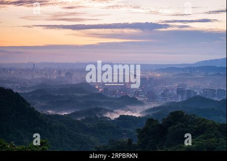 In der Abenddämmerung, der herrliche Himmel und die Silhouette der Stadt am Fluss. Blick auf die Stadtlandschaft vom Dajianshan Mountain, New Taipei City, Taiwan. Stockfoto