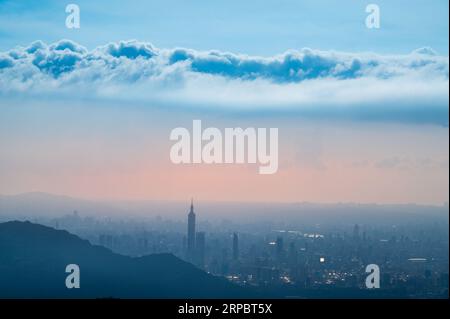 Twilight Transformation: Städtische Landschaft umgeben von Regenwolken. Blick auf die Stadtlandschaft vom Dajianshan Mountain, New Taipei City, Taiwan Stockfoto