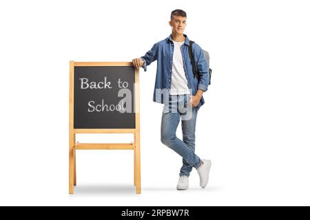 Portrait eines männlichen Teenagers mit einem Rucksack auf einer Tafel mit Text zurück zur Schule isoliert auf weißem Hintergrund Stockfoto