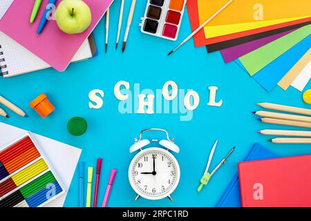 Farbenfrohe Schulsachen auf blauem Hintergrund, „Back to School“-Konzept. Stockfoto
