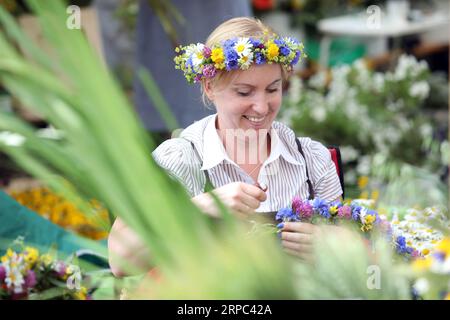 (190622) -- RIGA, 22. Juni 2019 -- Eine Frau macht Blumenkronen während des Midsummer Festival Ligo Market in Riga, Lettland, 21. Juni 2019. Am Freitag wurde hier das jährliche Mittsommerfest Ligo Market eröffnet, bei dem Bauern und Handwerker aus ganz Lettland Spezialitäten wie ländliches Brot, Käse, traditionellen Tee, Honig, handgemachte Kuchen und Kapillen verkaufen. ) LETTLAND-RIGA-MIDSUMMER FESTIVAL LIGO MARKET EDIJSXPALENS PUBLICATIONXNOTXINXCHN Stockfoto