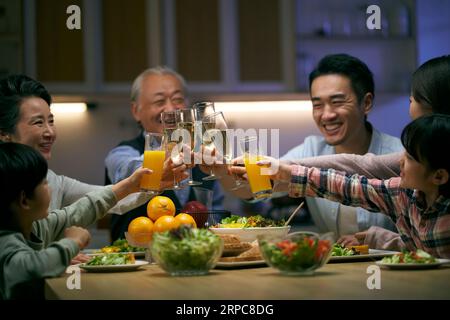 Eine asiatische Familie aus drei Generationen zu Hause, die den Urlaub mit einem Toast feiert Stockfoto