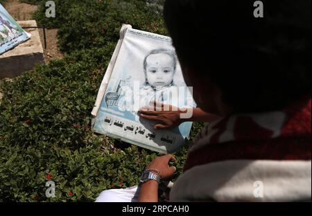 (190629) -- SANAA, 29. Juni 2019 -- Ein Mann reinigt Ein Bild eines Kindes, das während des laufenden Krieges auf einem Friedhof in Sanaa, Jemen, am 29. Juni 2019 getötet wurde. Mohammed Mohammed) JEMEN-SANAA-WAR-RUCKELLEBER nieyunpeng PUBLICATIONxNOTxINxCHN Stockfoto