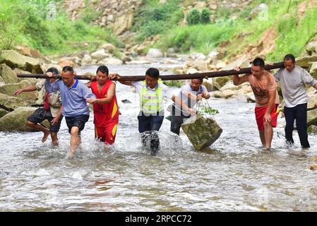 (190701) -- PEKING, 1. Juli 2019 -- Wei Guihua (4. R), Sekretär der Kommunistischen Partei Chinas, trägt einen Stein mit Parteimitgliedern und Dorfbewohnern, um einen Deich in Wuying zu verstärken, einem ethnischen Miao-Dorf, das an Chinas südwestliche Provinz Guizhou und die südliche autonome Region Guangxi Zhuang grenzt, 30. Juni 2019. ) XINHUA FOTOS DES TAGES HuangxXiaobang PUBLICATIONxNOTxINxCHN Stockfoto