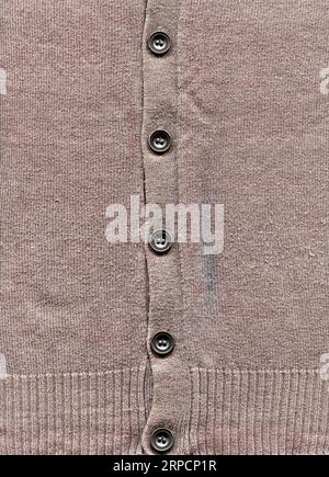 Gemusterte Strickjacke aus Wolle. Handgefertigter Strickstoff grauer Wollpullover mit Hintergrundtextur und grauen Knöpfen Stockfoto