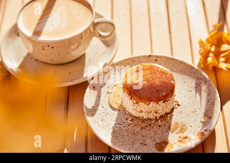 Sonniges gesundes Karottendessert im Herbst mit Agavensirup. Kuchen mit einer Tasse Kaffee unter harten Schatten. Frühstück im Freien. Stockfoto
