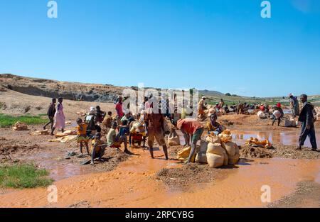 Ihosy, Ilakaka, Madagaskar - 20. November 2022: Die Einheimischen suchen nach Edelsteinen und Pfannen nach Gold in einem Fluss. Die Stadt ist ein wichtiges Zentrum für Saphirprodukte Stockfoto