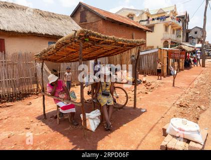 Mandoto, Madagaskar - 9. November 2022: Überfüllter Straßenmarkt in der Stadt Mandoto, mit Händlern und einfachen Menschen, die einkaufen und sich unterhalten. Frau verkauft Stockfoto