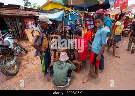 Mandoto, Madagaskar - 2. November 2022: Ein madagassischer Mann wird auf den Straßen von Mandoto gesehen, wie er an der Reparatur von Telefonsoftware mit einem Laptop arbeitet. Stockfoto