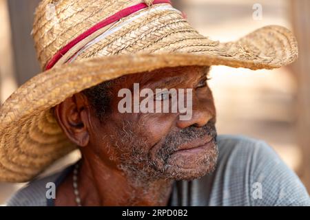 Miandrivazo, Madagaskar - 2. November 2022 - älterer Mann, der einen Strohhut trägt und lächelt. Älterer Mann, der auf der Straße ruht. Stockfoto