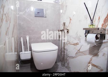 Modernes Bad mit wandhängender Toilette und grauen Feinsteinzeugfliesen. Stockfoto