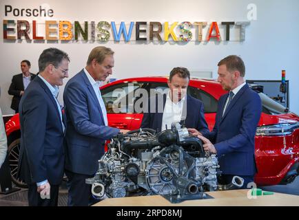 September 2023, Sachsen, Leipzig: Gerd Rupp (2. von rechts), Vorsitzender des Vorstands der Porsche Leipzig GmbH, erklärt in der Porsche Experience Werkstatt Michael Kretschmer (r, CDU), Ministerpräsident von Sachsen, sowie Adrian Willig (l), VDI-Direktor, und Burkhard Jung (SPD), Bürgermeister von Leipzig, einen 4-Zylinder-Boxermotor. Der Automobilhersteller Porsche hat seine Nachwuchsförderung in Leipzig mit dem Porsche Experience Workshop erweitert. Ziel ist es, Kindern und Jugendlichen der Klassen drei bis neun spielerischen Zugang zu Mathematik, Informatik und Naturwissenschaften zu ermöglichen Stockfoto