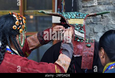 (190728) -- LHASA, 28. Juli 2019 -- Eine Frau zieht Burang Kleidung mit Hilfe in Burang County von Ali an, Südwestchinas autonome Region Tibet, 22. Juli 2019. Burang Kleidung, die traditionell in Burang County of Ali getragen wird, hat eine Geschichte von mehr als 1.000 Jahren. Ein Anzug kann etwa 25 kg wiegen, da er mit Gold, Silber, Perlen und anderen Juwelen verziert ist. ) CHINA-TIBET-ALI-BURANG CLOTHES (CN) CHOGO PUBLICATIONXNOTXINXCHN Stockfoto