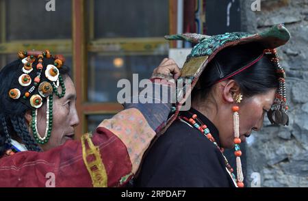 (190728) -- LHASA, 28. Juli 2019 -- Eine Frau zieht Burang Kleidung mit Hilfe in Burang County von Ali an, Südwestchinas autonome Region Tibet, 22. Juli 2019. Burang Kleidung, die traditionell in Burang County of Ali getragen wird, hat eine Geschichte von mehr als 1.000 Jahren. Ein Anzug kann etwa 25 kg wiegen, da er mit Gold, Silber, Perlen und anderen Juwelen verziert ist. ) CHINA-TIBET-ALI-BURANG CLOTHES (CN) CHOGO PUBLICATIONXNOTXINXCHN Stockfoto