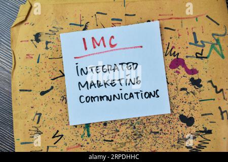 IMC-Konzept – integrierte Marketingkommunikation Schreiben Sie auf Haftnotizen, die auf einem Holztisch isoliert sind. Stockfoto