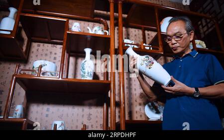 (190805) -- NANCHANG, 5. Aug. 2019 -- Mao Guanghui überprüft in seinem Atelier in Jingdezhen, Ostchinesische Provinz Jiangxi, 1. Aug. 2019 ein Stück bemaltes Porzellan. Mao Guanghui, ein 56-jähriger älterer Meister der Kunst und des Handwerks in der Provinz Jiangxi, widmet sich seit seinem 13. Lebensjahr der Porzellanmalerei. Als Schüler von Deng Bishan (1874–1930), einem der acht Freunde von Zhushan, einer Gruppe von Jingdezhen-Künstlern, die weithin für ihre Innovationen in der Porzellanmalerei bekannt sind, erbte Mao nicht nur die Fähigkeiten, sondern auch die Kunst, Porzellanmalereien zu schaffen. Das Thema Stockfoto