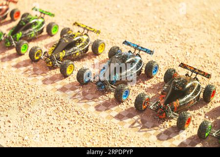 Mehrere bunte Buggys mit Fernbedienung auf der Startlinie in der Wüste. Stockfoto